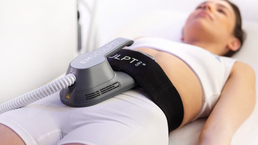 Non-invasive EMSculpt applicator strapped to a person’s abdomen during treatment.